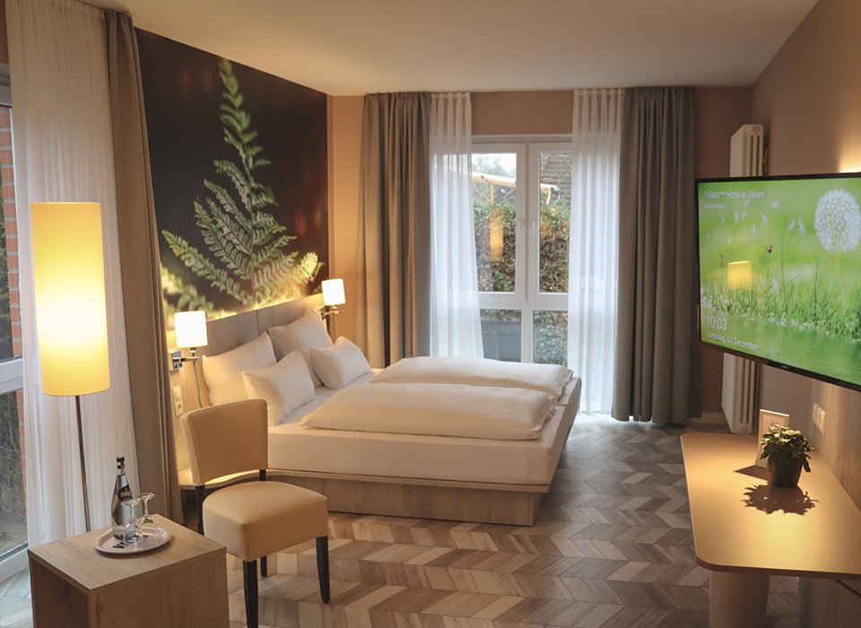 Zweibettzimmer mit Sessel und großem Fernseher